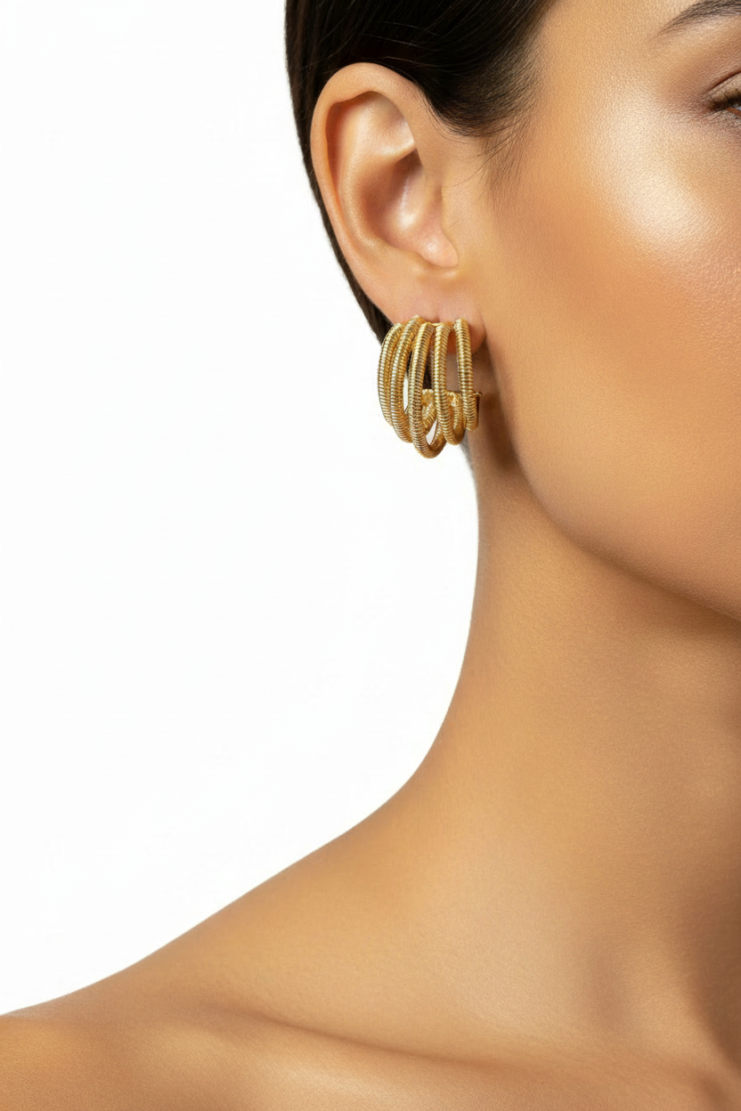 Model wearing gold triple-coil textured hoop earrings, close-up on ear and neck